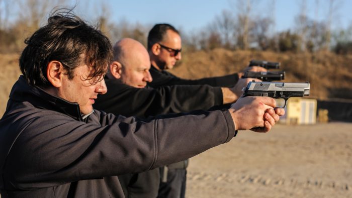 Group of people practice gun shooting on outdoor shooting range