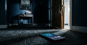 Smartphone on the floor showing an active 911 call in front of a splintered, forced-open door